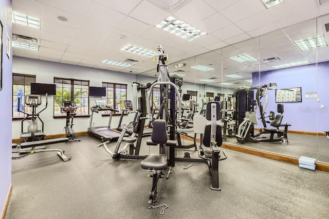 workout area featuring baseboards and a drop ceiling