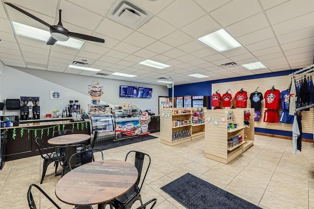 misc room with a ceiling fan, a paneled ceiling, and light tile patterned floors