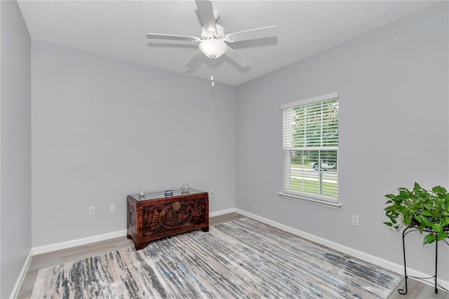 spare room with wood finished floors, a ceiling fan, and baseboards