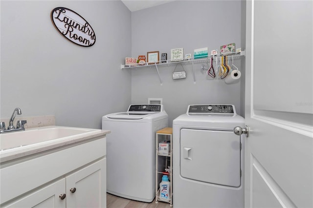 clothes washing area with washer and clothes dryer, cabinet space, and light wood finished floors