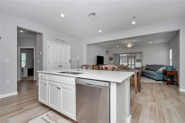 kitchen with stainless steel dishwasher, a sink, open floor plan, light wood-style floors, and recessed lighting