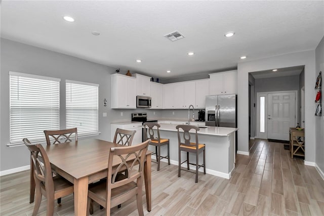 dining room with light wood finished floors, baseboards, and recessed lighting