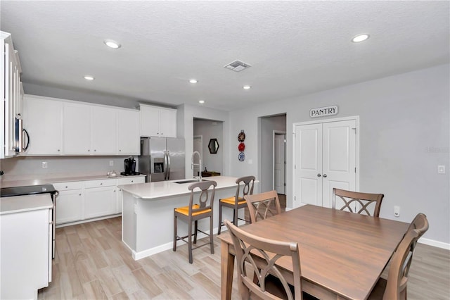 dining area featuring light wood-style flooring, baseboards, recessed lighting, and a textured ceiling