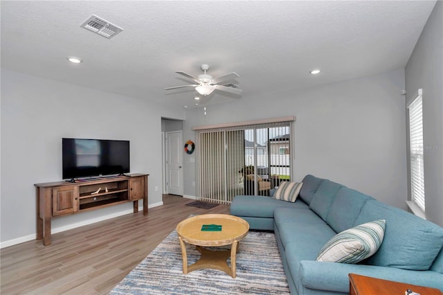 living room with a ceiling fan, light wood finished floors, baseboards, recessed lighting, and a textured ceiling