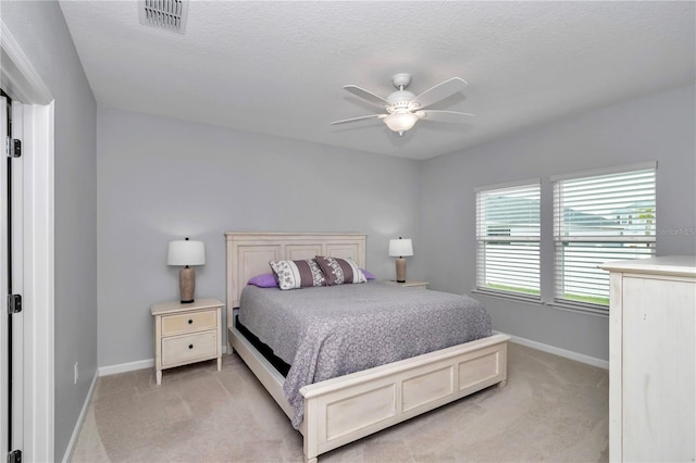 bedroom with light colored carpet, baseboards, a ceiling fan, and a textured ceiling
