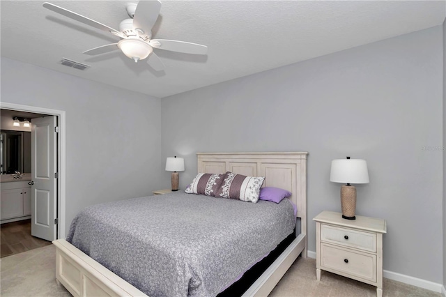 bedroom featuring light colored carpet, a ceiling fan, connected bathroom, and baseboards
