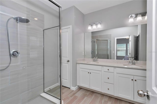 full bath featuring a shower stall, double vanity, and wood finished floors