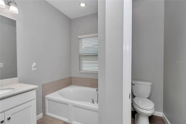 bathroom with vanity, a garden tub, and toilet