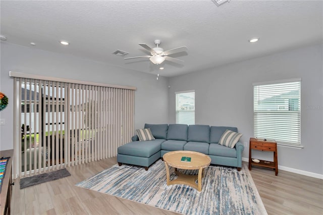 living area featuring ceiling fan, light wood-type flooring, recessed lighting, baseboards, and a textured ceiling