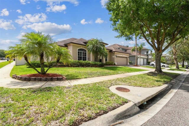 14003 Sobrado Dr, Orlando, FL 32837 - mediterranean / spanish-style house with stucco siding, an attached garage, a front lawn, and concrete driveway