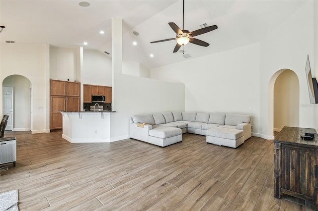 14003 Sobrado Dr, Orlando, FL 32837 - living room with arched walkways, high vaulted ceiling, ceiling fan, light wood-style floors, and baseboards