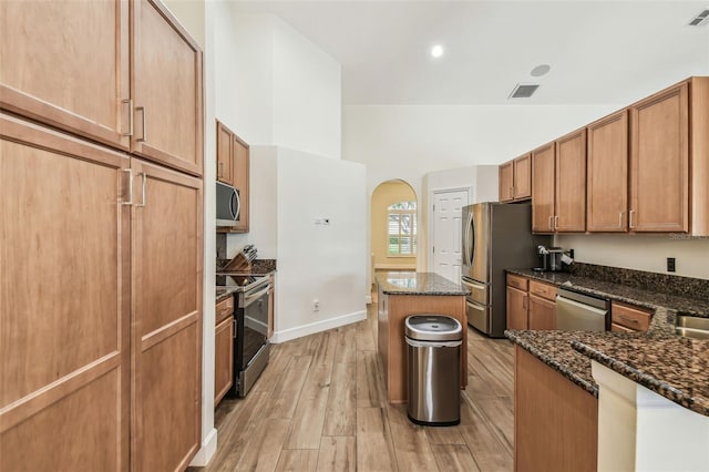 14003 Sobrado Dr, Orlando, FL 32837 - kitchen with stainless steel appliances, a kitchen island, light wood-style flooring, dark stone countertops, and recessed lighting