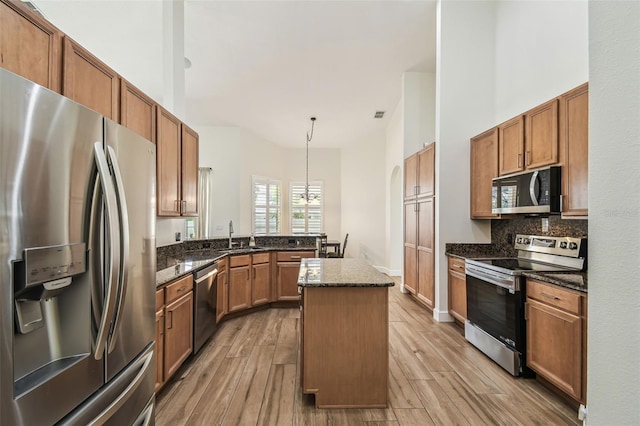 14003 Sobrado Dr, Orlando, FL 32837 - kitchen with stainless steel appliances, light wood-type flooring, backsplash, a center island, and dark stone counters