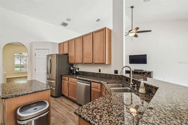 14003 Sobrado Dr, Orlando, FL 32837 - kitchen with stainless steel appliances, a sink, arched walkways, a ceiling fan, and light wood-type flooring
