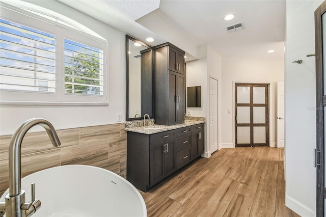 14003 Sobrado Dr, Orlando, FL 32837 - full bath with a freestanding tub, wood finished floors, vanity, recessed lighting, and tile walls