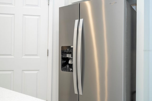 kitchen view of stainless steel fridge, white cabinets, and light countertops