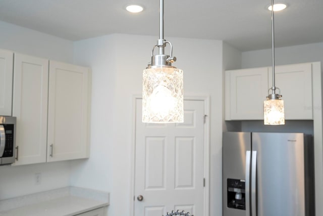 kitchen featuring pendant lighting, stainless steel appliances, light countertops, and white cabinets