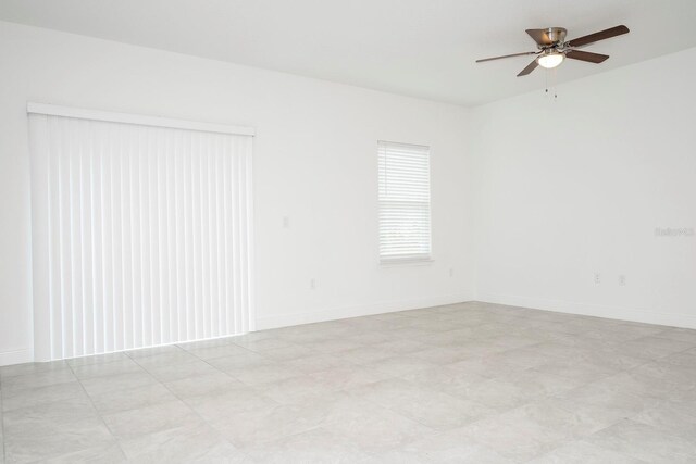 spare room featuring a ceiling fan and baseboards