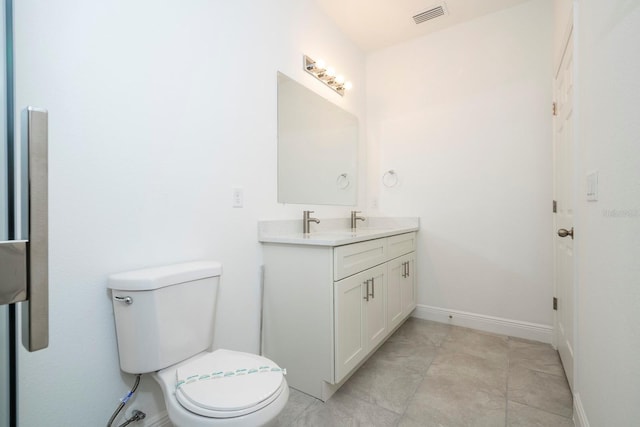 bathroom with toilet, vanity, and baseboards