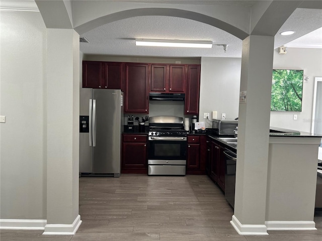 14501 Grove Resort Unit 1409, Winter Garden, FL 34787 - kitchen featuring stainless steel appliances, dark countertops, extractor fan, reddish brown cabinets, and arched walkways