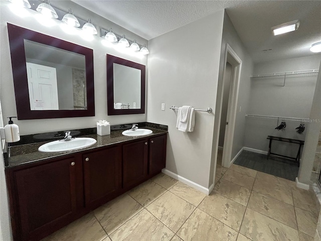 14501 Grove Resort Unit 1409, Winter Garden, FL 34787 - bathroom with a walk in closet, double vanity, a textured ceiling, and baseboards