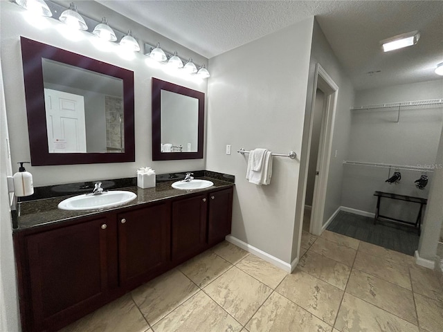 14501 Grove Resort Unit 1409, Winter Garden, FL 34787 - full bathroom featuring a walk in closet, double vanity, a textured ceiling, and baseboards