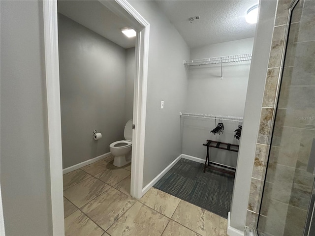 14501 Grove Resort Unit 1409, Winter Garden, FL 34787 - bathroom featuring a walk in closet, toilet, a tile shower, a textured ceiling, and baseboards