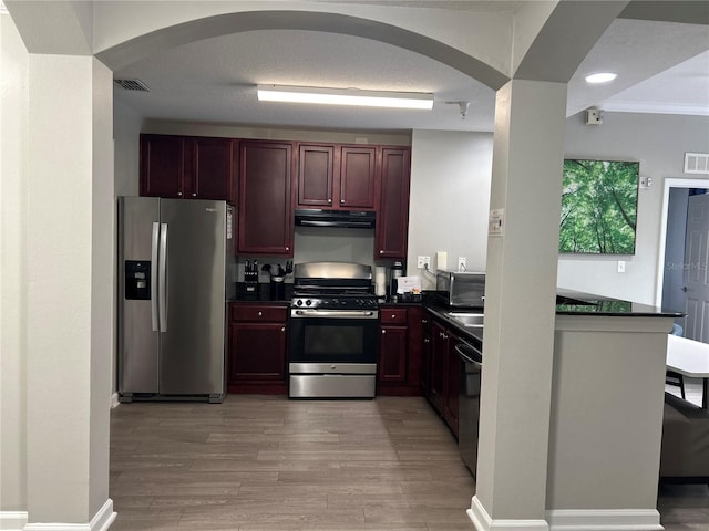 14501 Grove Resort Unit 1409, Winter Garden, FL 34787 - kitchen with stainless steel appliances, arched walkways, dark countertops, reddish brown cabinets, and crown molding