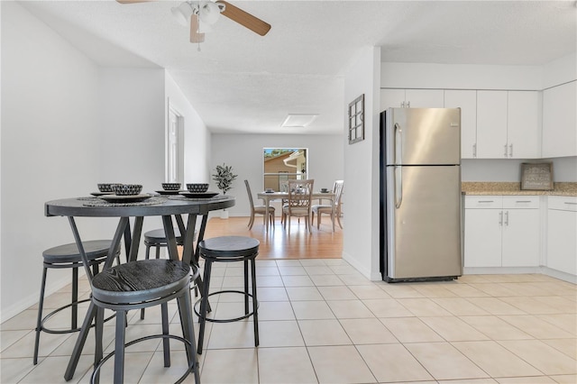 dining room with ceiling fan, a textured ceiling, light tile patterned floors, and baseboards