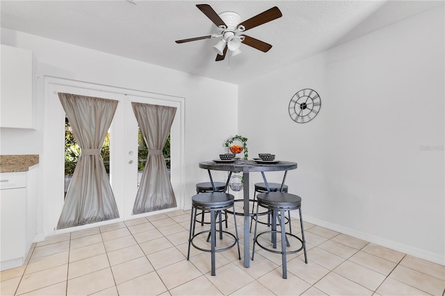 dining room featuring a ceiling fan, light tile patterned flooring, baseboards, french doors, and a textured ceiling