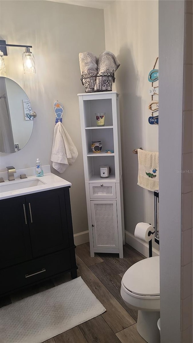 bathroom featuring wood finished floors, vanity, toilet, and baseboards