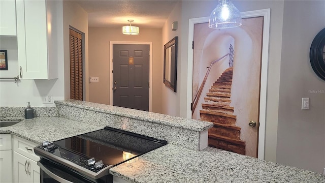kitchen featuring electric range oven, white cabinetry, light stone counters, a peninsula, and pendant lighting