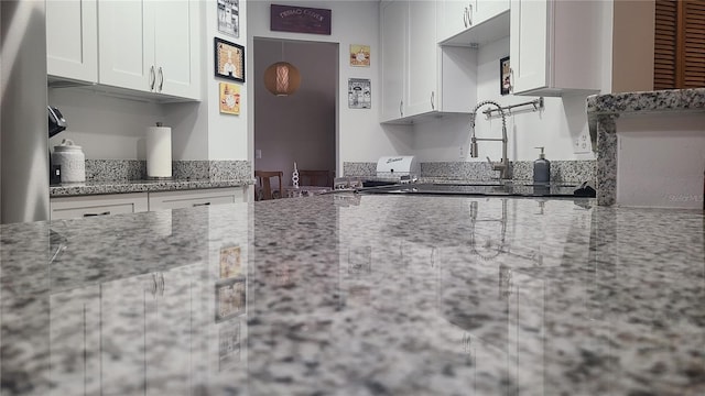 kitchen featuring white cabinets, light stone countertops, and a sink