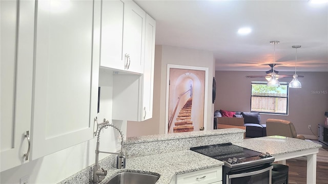 kitchen featuring electric stove, white cabinetry, a sink, light stone countertops, and recessed lighting