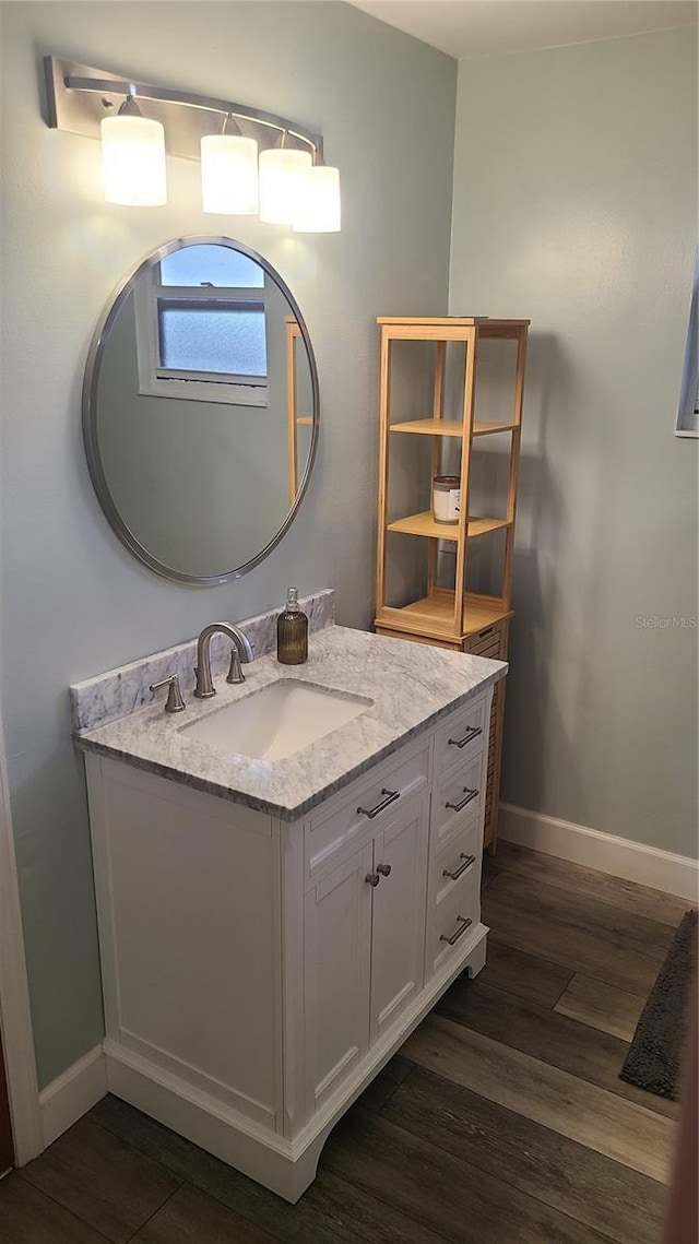 bathroom with baseboards, wood finished floors, and vanity