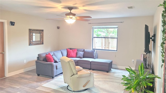 living room featuring ceiling fan, baseboards, and light wood-style floors