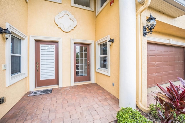 entrance to property with stucco siding and a garage