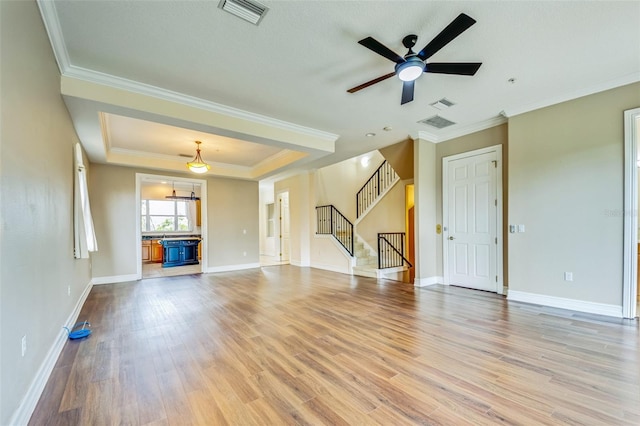 unfurnished living room with light wood-type flooring, ceiling fan, stairway, baseboards, and ornamental molding