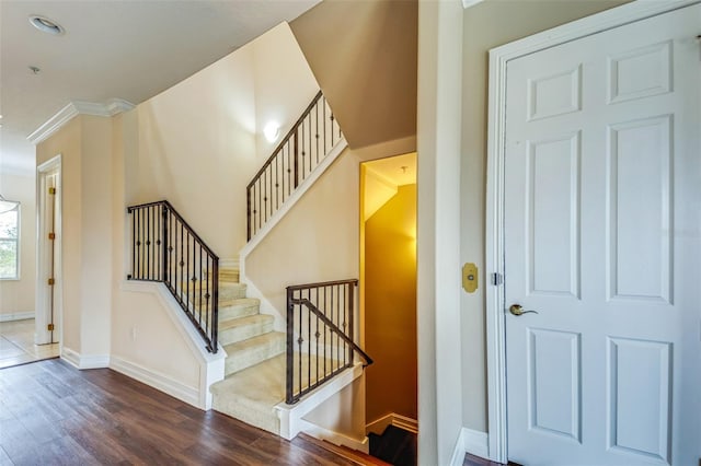 stairs featuring wood finished floors, baseboards, and crown molding