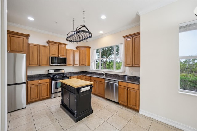 kitchen with appliances with stainless steel finishes, a sink, plenty of natural light, light tile patterned floors, and crown molding
