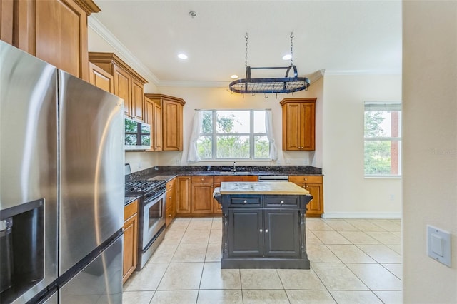 kitchen featuring stainless steel appliances, ornamental molding, a sink, healthy amount of natural light, and brown cabinets