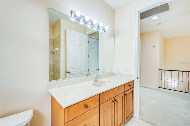 bathroom with toilet, vanity, and tiled shower