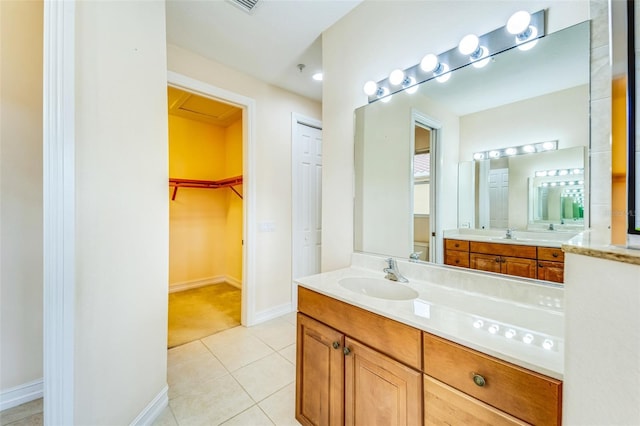 bathroom featuring tile patterned floors, toilet, vanity, baseboards, and a walk in closet
