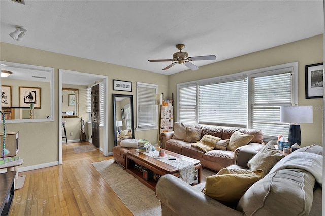 living room with baseboards, a ceiling fan, and light wood-style floors