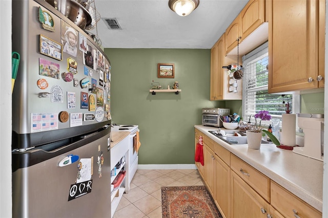 kitchen featuring freestanding refrigerator, light tile patterned flooring, light countertops, and light brown cabinetry
