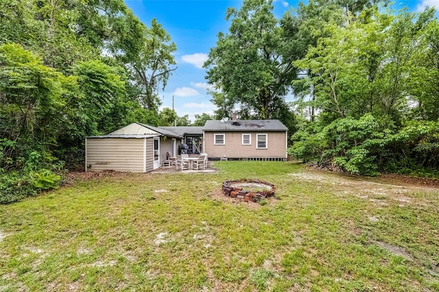 rear view of property with an outdoor fire pit, a patio area, and a lawn