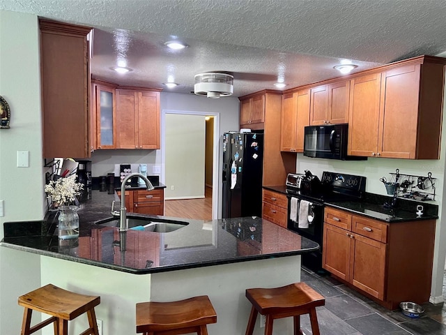 1430 Arrowhead Trl, Deltona, FL 32725 - kitchen with black appliances, a sink, a peninsula, a kitchen bar, and a textured ceiling