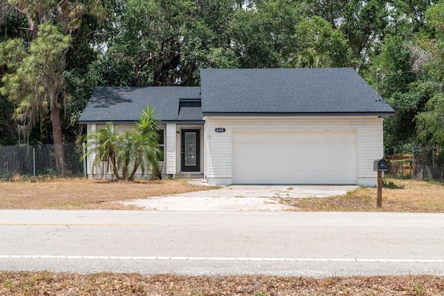 view of front of property featuring fence, driveway, a garage, a shingled roof, and view of scattered trees
