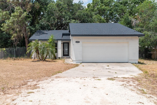 view of front of property with fence, concrete driveway, an attached garage, a shingled roof, and view of scattered trees