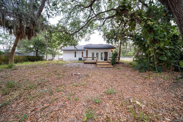 back of property with a wooden deck, french doors, and fence
